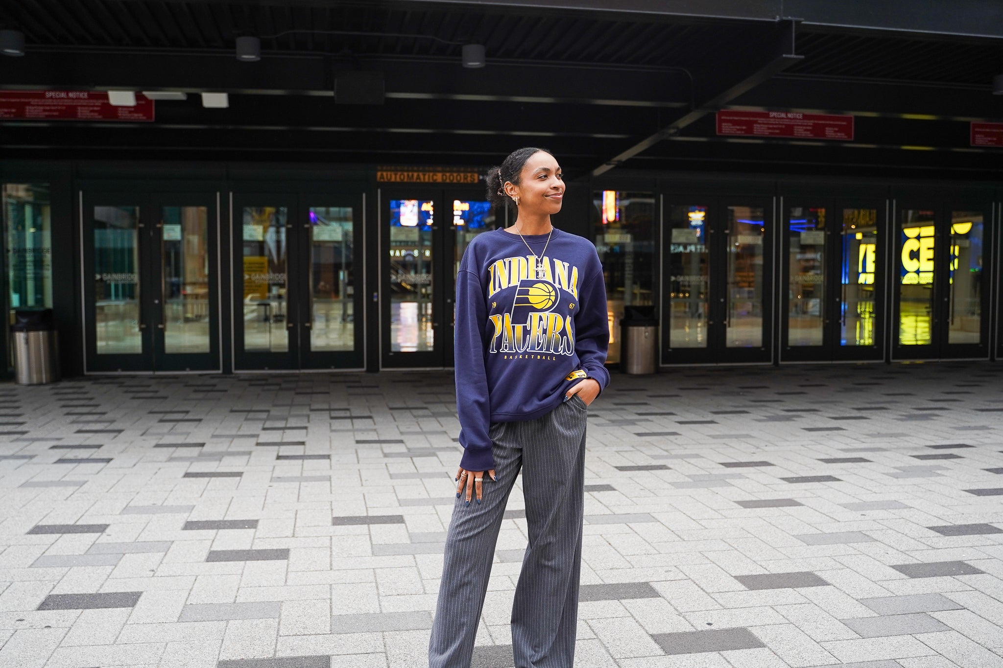 Person wearing an Indiana Pacers sweatshirt standing in a covered outdoor area.