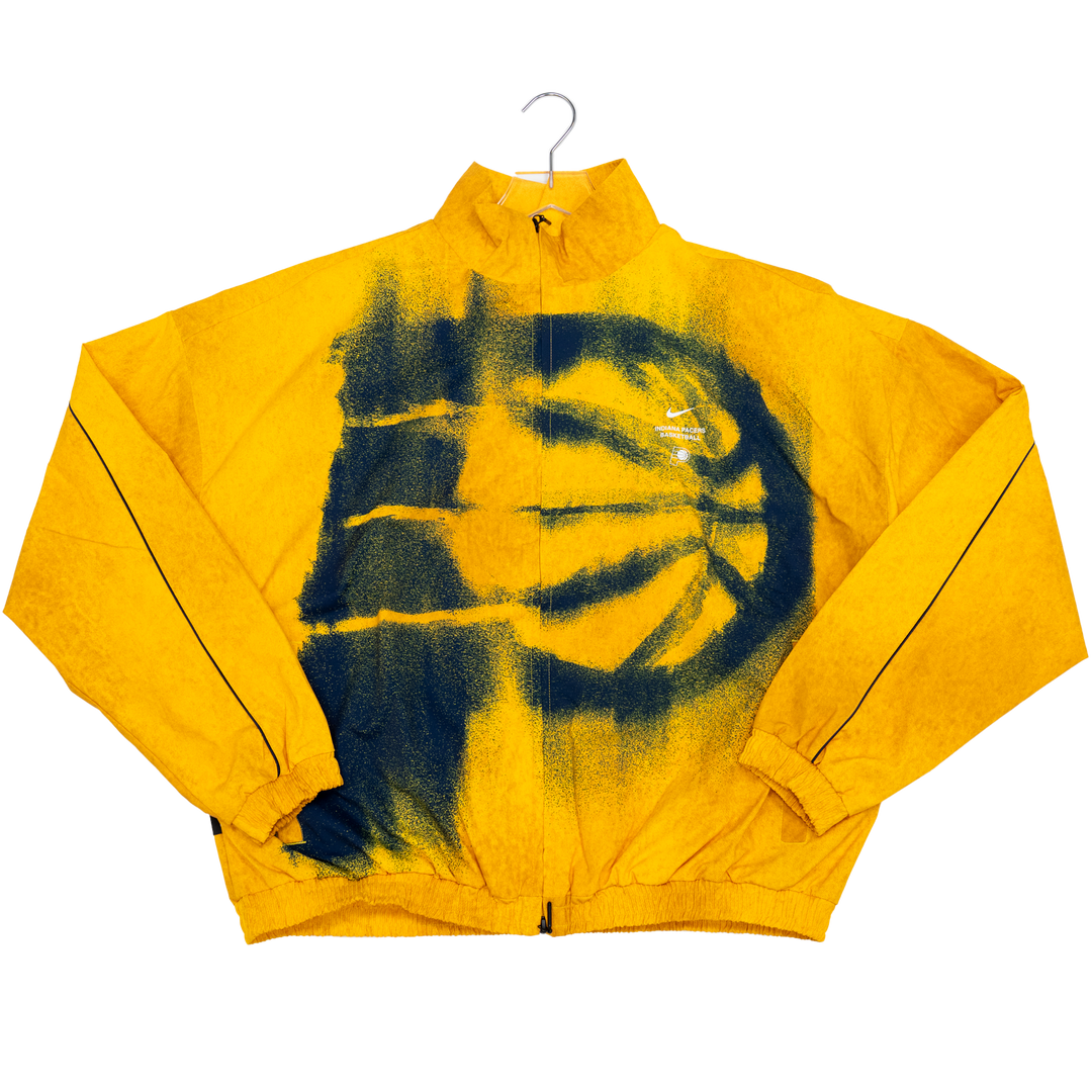 A yellow zip-up windbreaker jacket with a large black spray-paint style graphic of a basketball and face on the front, hanging on a metal hanger against a white background.