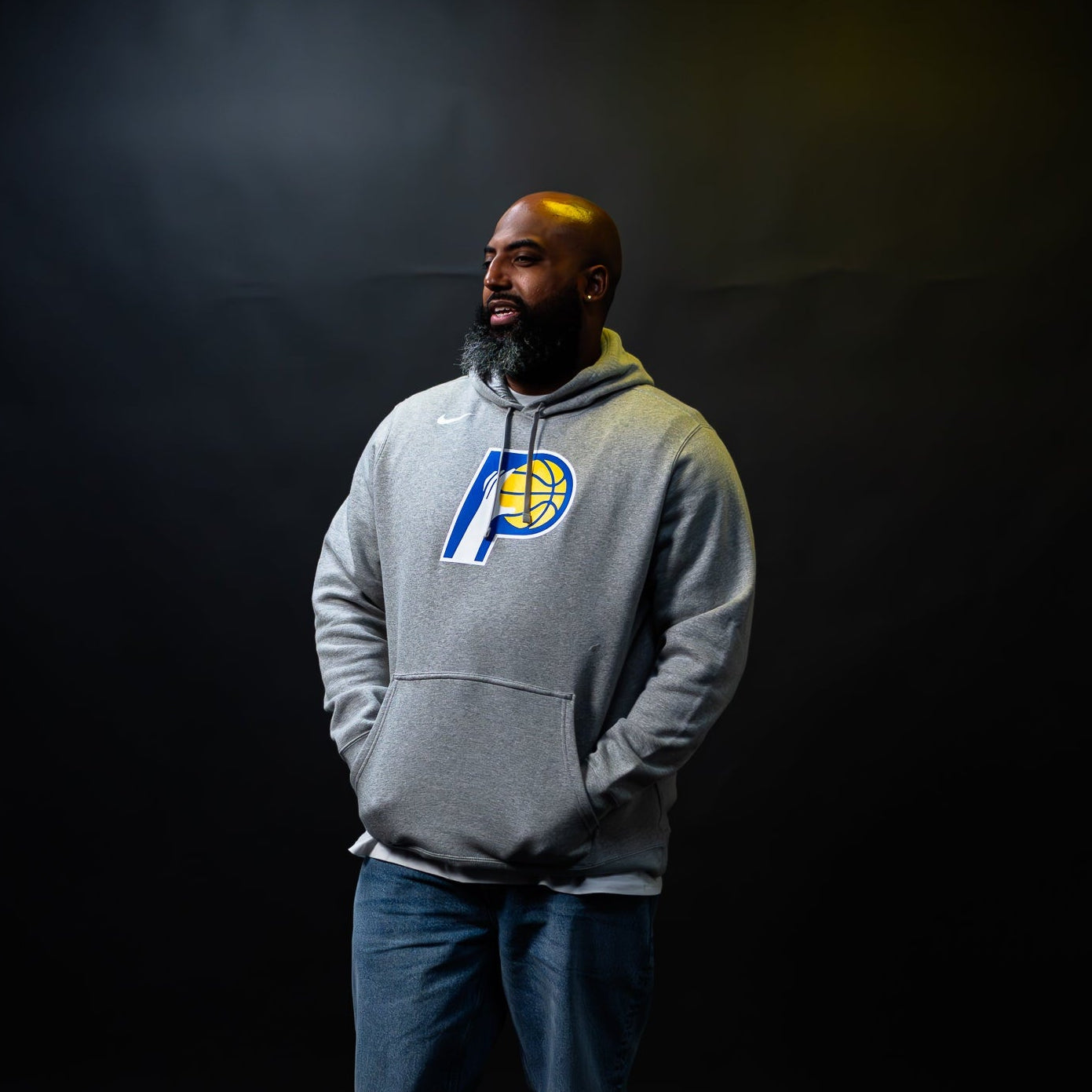 Man wearing a gray hoodie with a logo against a black background