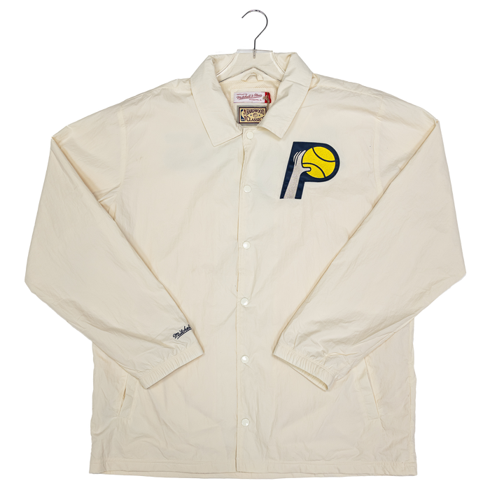 An off-white/cream long-sleeve button-up coach jacket from Mitchell &amp; Ness, displayed on a hanger against a white background. It features the Indiana Pacers logo embroidered on the left chest.