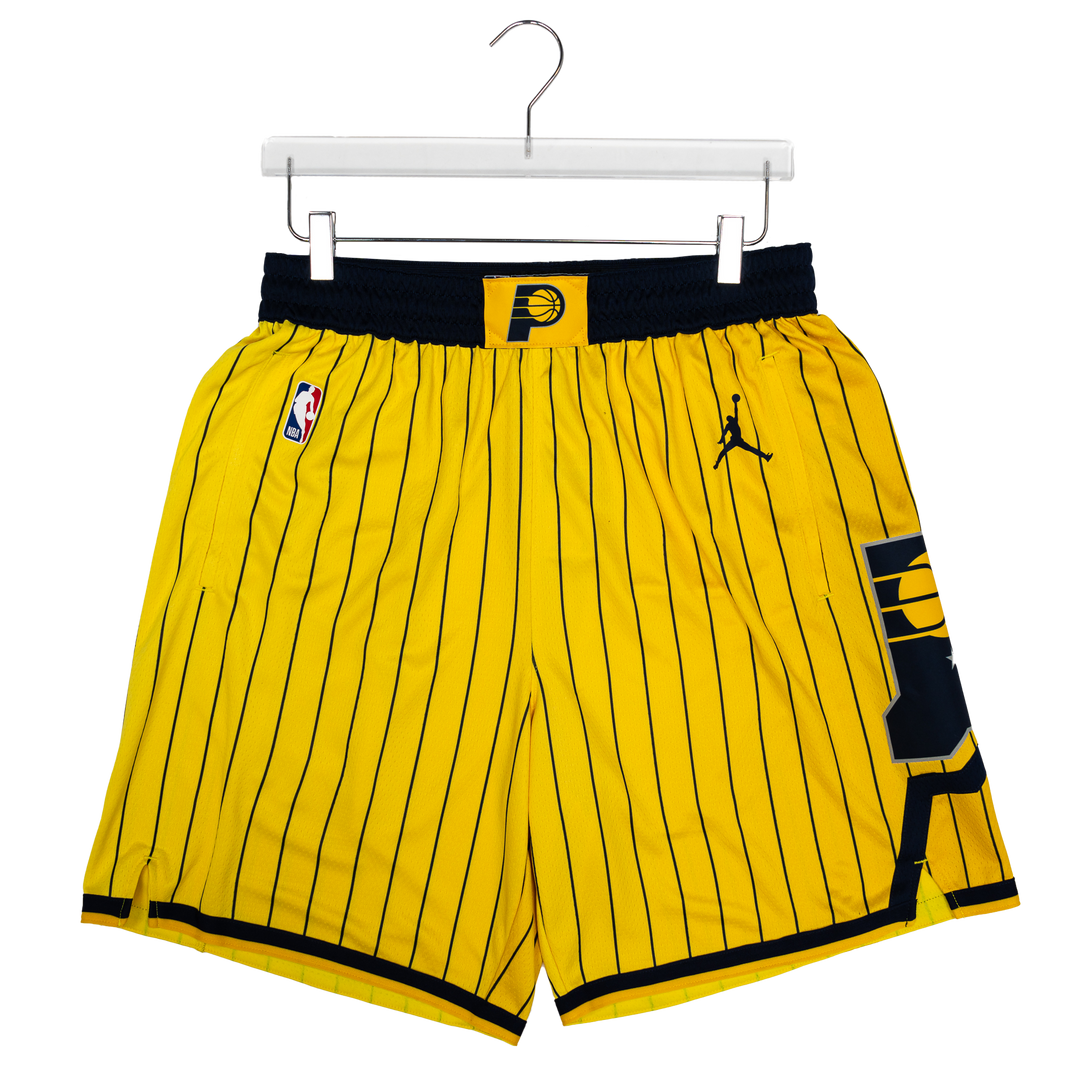 Yellow and black pinstripe basketball shorts featuring the Indiana Pacers logo, an NBA logo, and a Jordan logo, hanging on a white hanger against a white background.