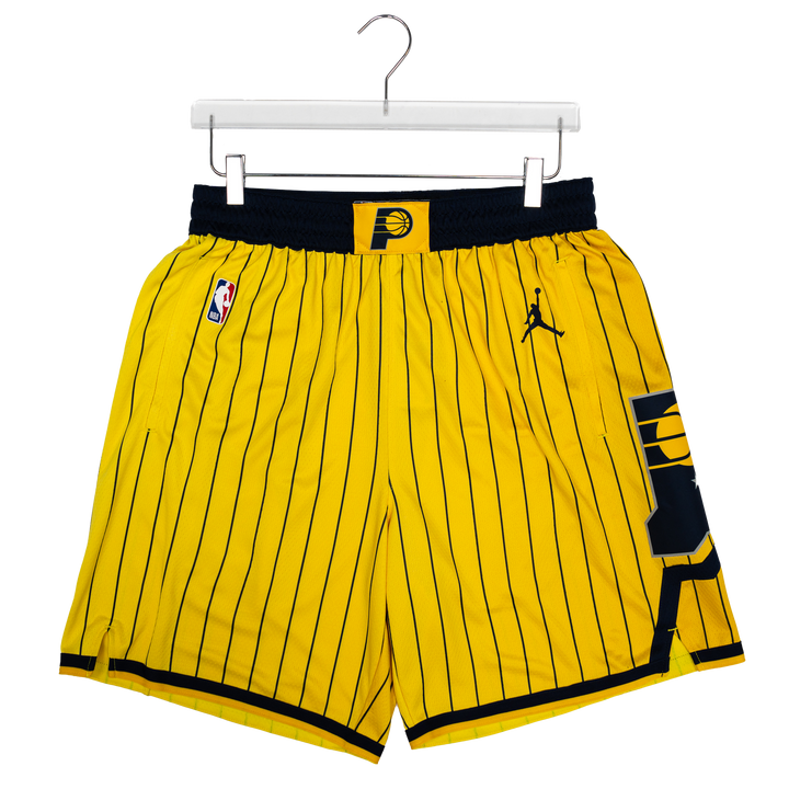 Yellow and black pinstripe basketball shorts featuring the Indiana Pacers logo, an NBA logo, and a Jordan logo, hanging on a white hanger against a white background.